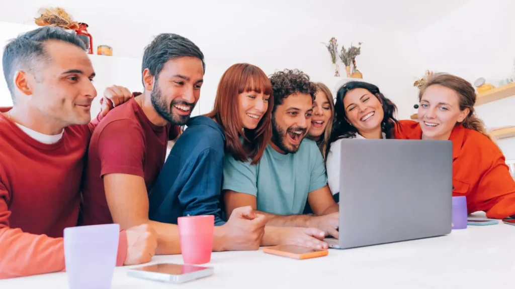 A group of people engaging with content on a laptop, reflecting the community and interaction vital for enhancing engagement in a digital marketing sales funnel.